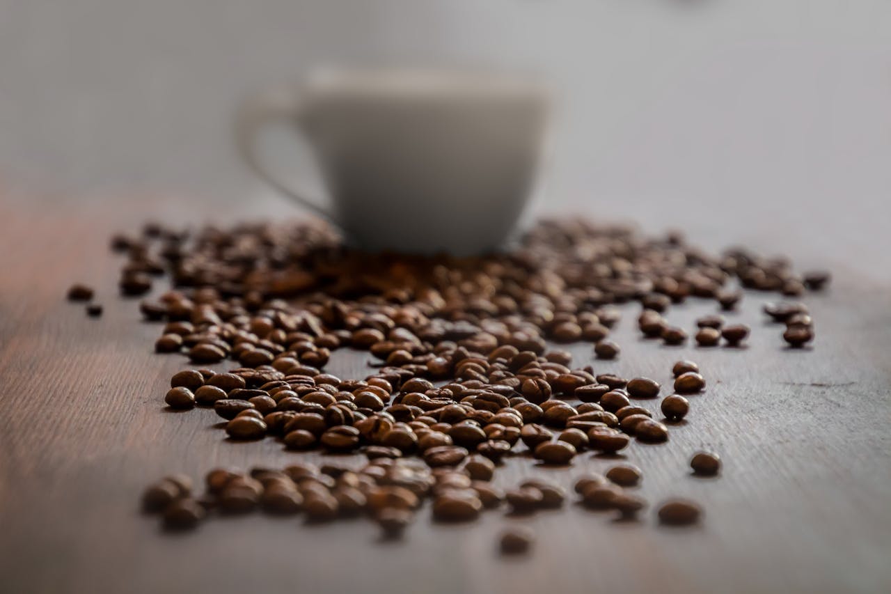 Grains de café torréfiés et tasse blanche sur une table en bois